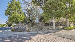 Una entrada empedrada de ladrillo con un muro de piedra y un cartel que dice