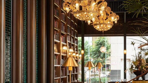 En lyxig lobby med en storslagen kristallkrona, marmorgolv och en välfylld bokhylla.