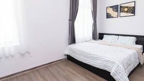 Un dormitorio con una cama, cortinas y dos obras de arte colgadas en la pared.