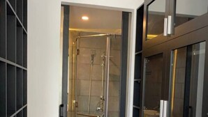 Un baño moderno con cabina de ducha de vidrio, inodoro y tocador con espejo.