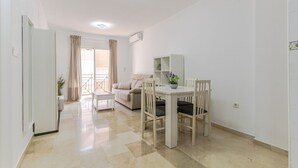 A modern apartment with a dining area, a sofa, and a balcony. - RentitSpain Varadero: Beach, Sea, and Comfort (Motril)