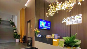 Un'area della reception di un hotel, con una scrivania, uno schermo digitale e una scala che conduce a un piano superiore.