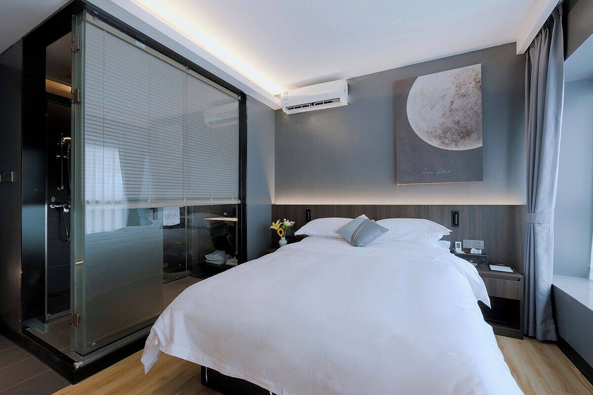 Ein modernes Hotelzimmer mit einem großen Bett, einem Schrank mit Glastüren, einer Klimaanlage, einem Nachttisch und einem Wandbild.