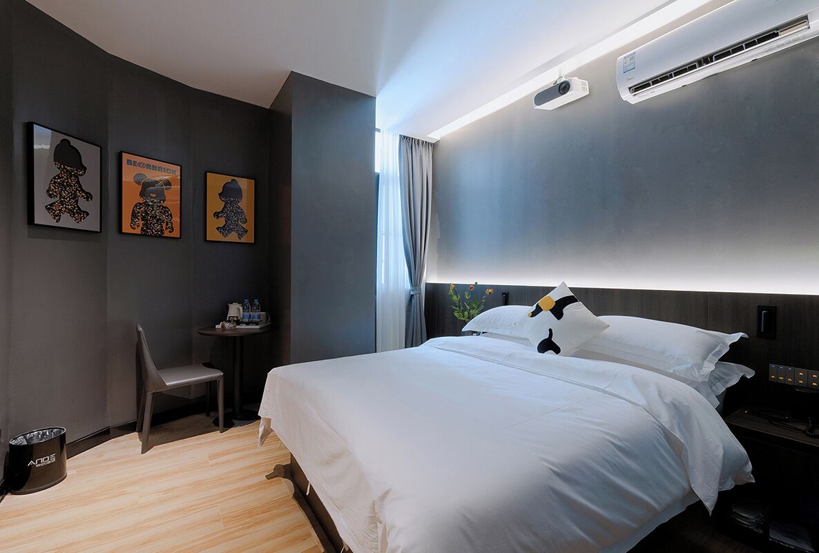 Ein modernes Hotelzimmer mit einem großen Bett, einem kleinen Tisch mit Stuhl und Bildern an der Wand.