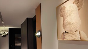 Un corridoio con un design d'interni moderno, caratterizzato da una porta in legno, un quadro appeso alla parete e un elemento decorativo circolare.