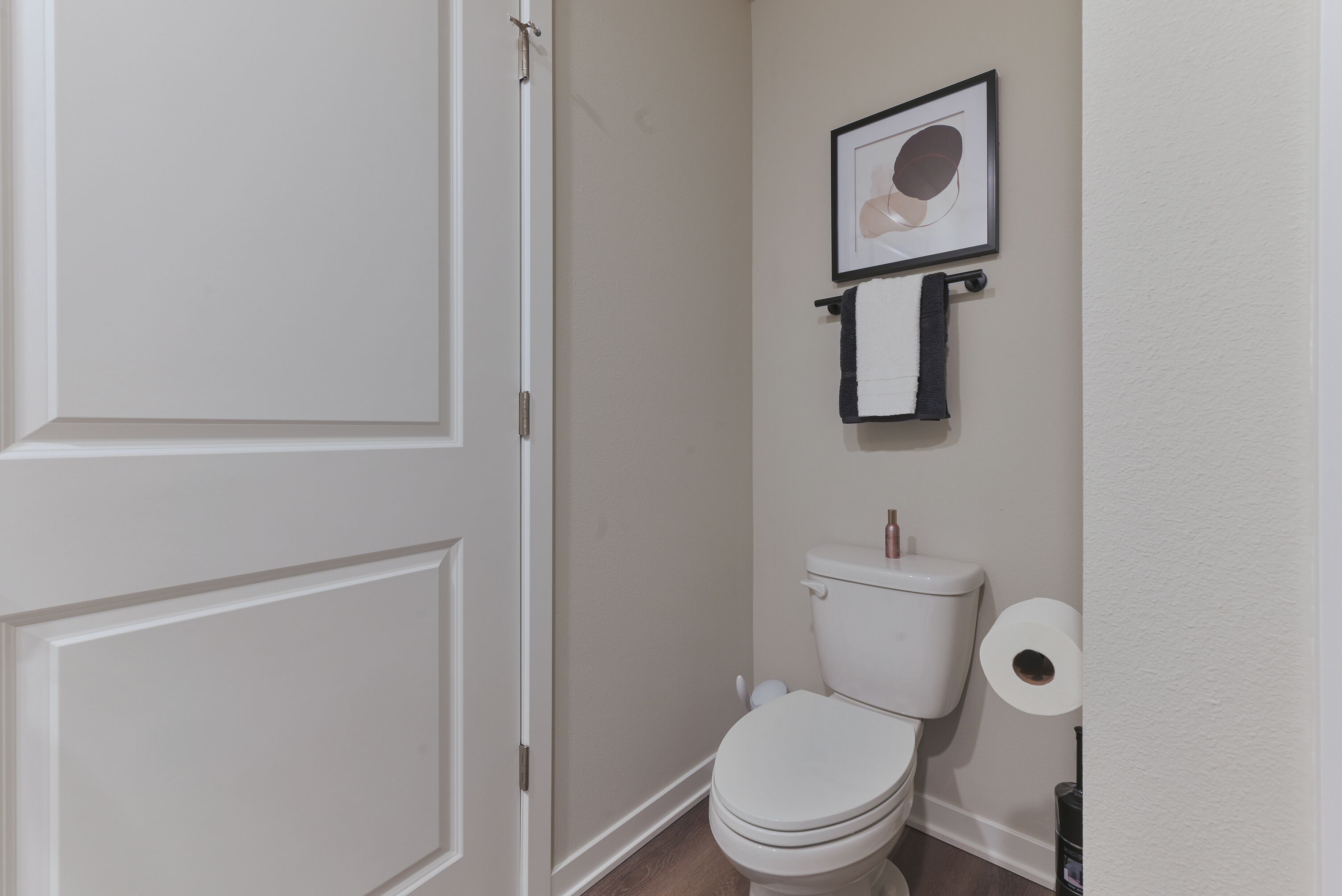 Une salle de bain avec des toilettes, un tableau encadré et un rouleau de papier toilette.