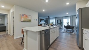 A modern kitchen with a central island, stainless steel appliances, and a dining area with a table and chairs.