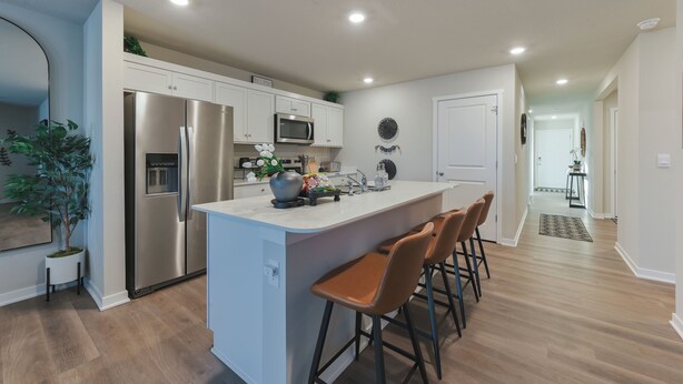 A modern kitchen with white cabinets, stainless steel appliances, and a central island with bar stools.