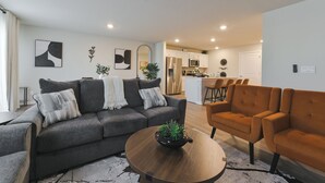 A modern living room with a grey sofa, an orange armchair, and a wooden coffee table.