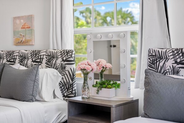 A room with a bed, a vanity with a mirror, and a window with curtains.