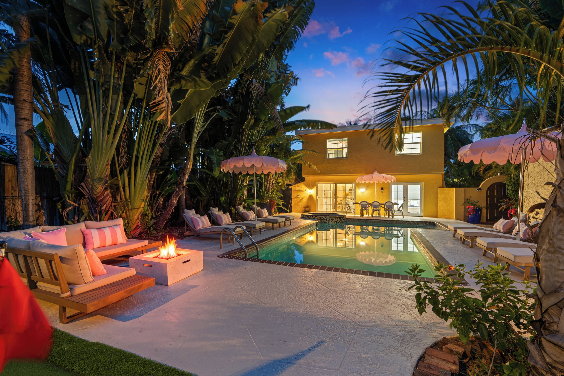 A modern house with a swimming pool, outdoor seating, and a fire pit.