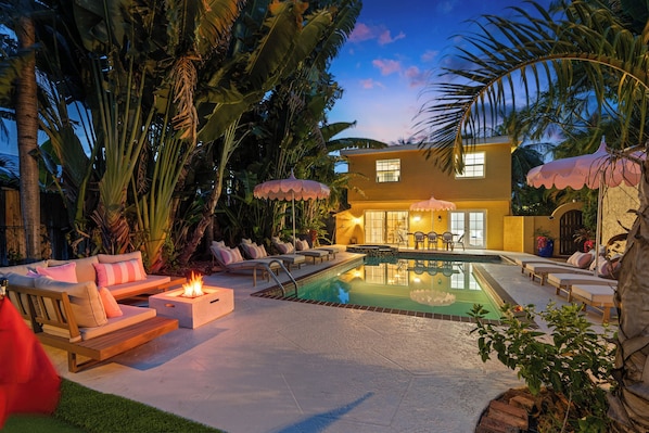 A modern house with a swimming pool, outdoor seating, and a fire pit.