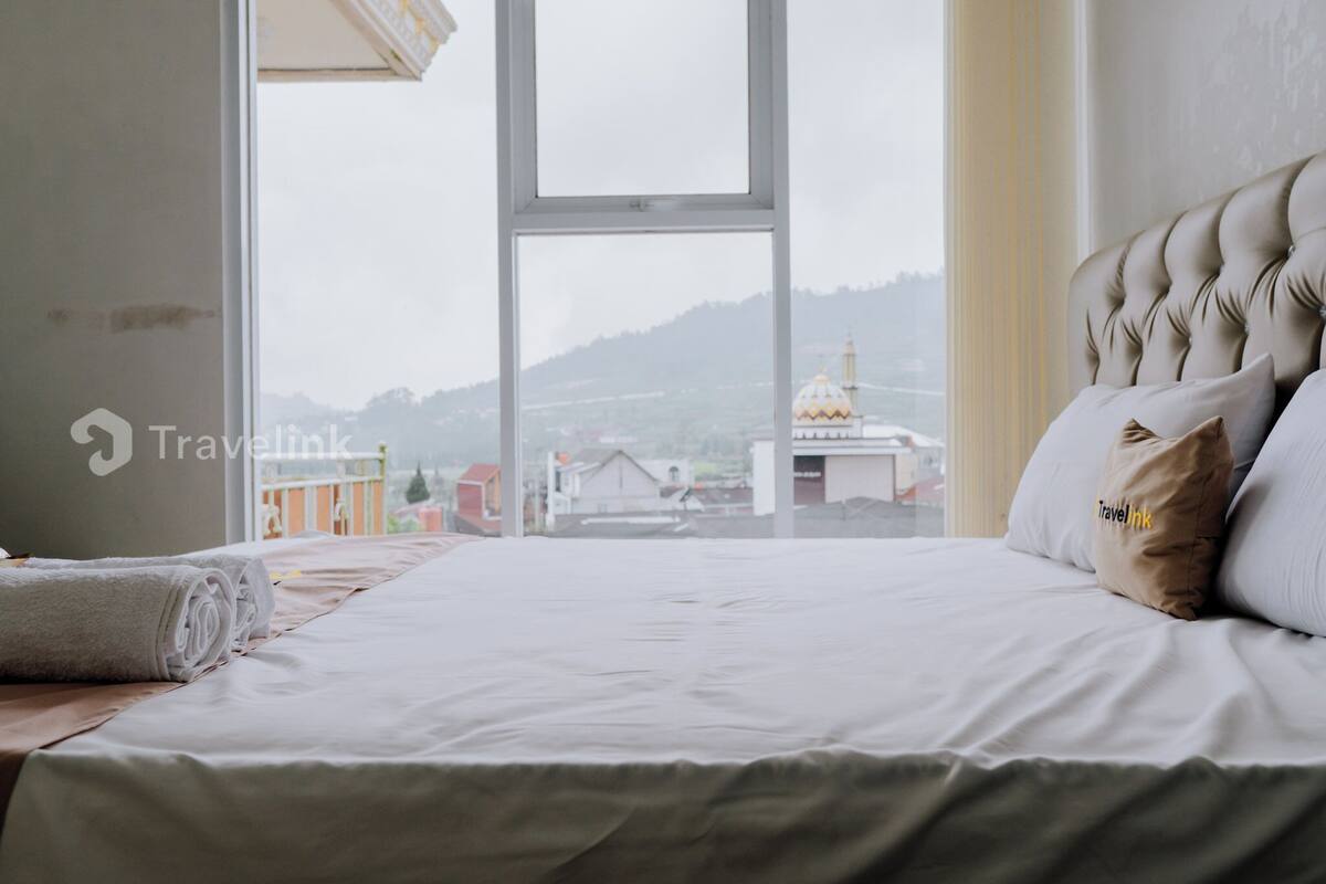 Un lit bien fait, avec vue sur un bâtiment doté d’un dôme, visible à travers une fenêtre.