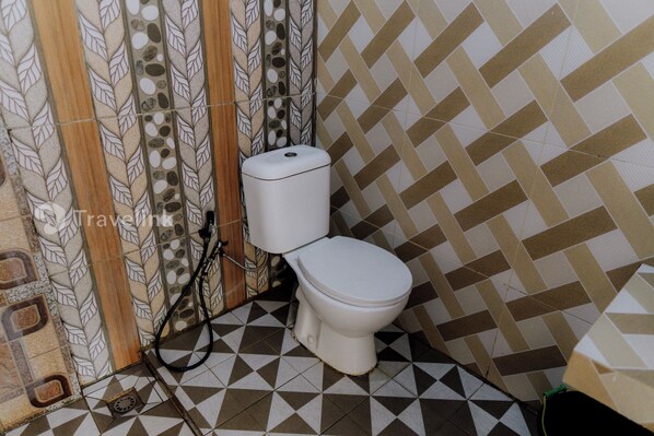 A bathroom with a toilet, patterned tiles, and a shower curtain.