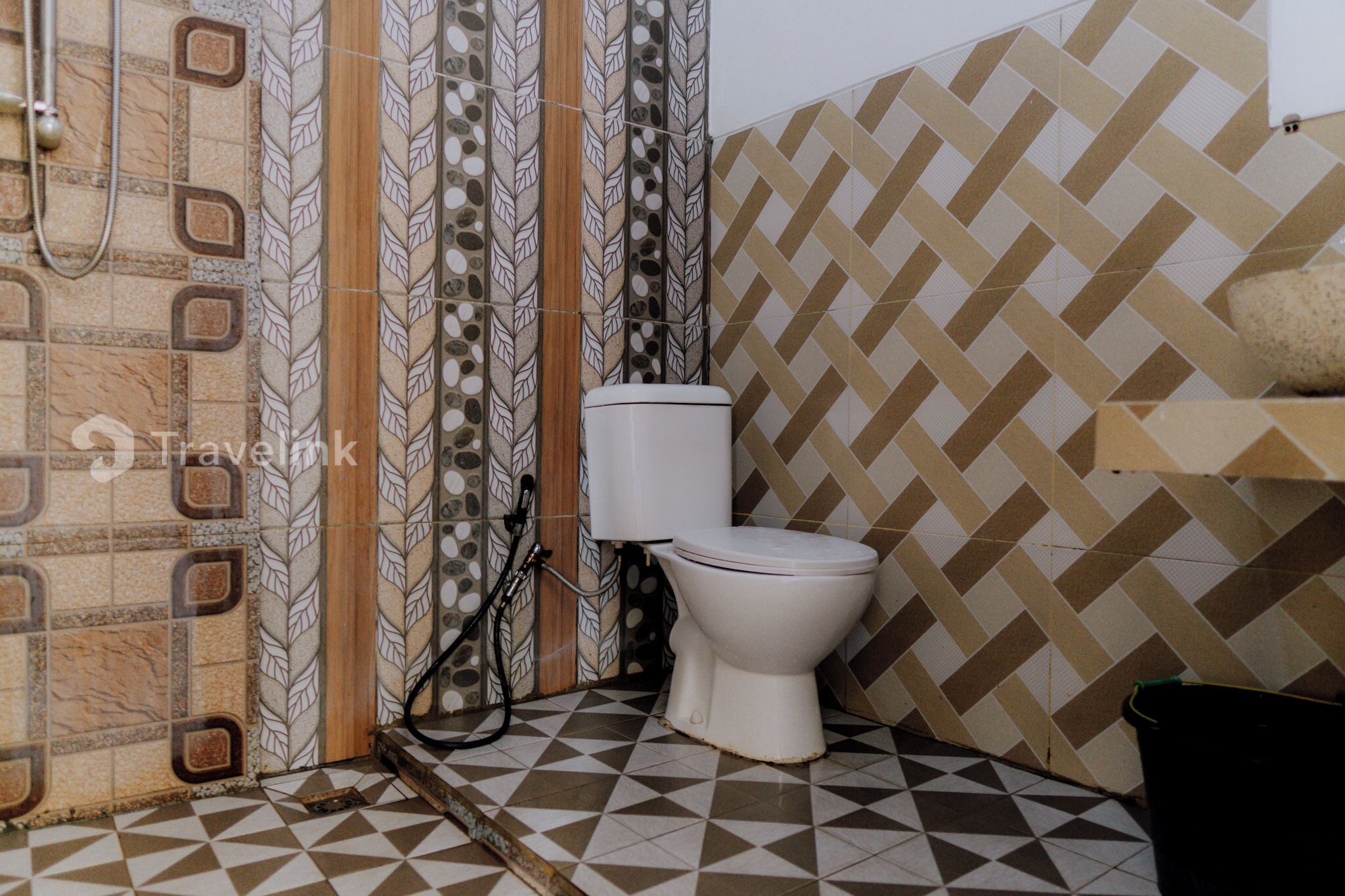 Un baño con inodoro, ducha y paredes de azulejos.