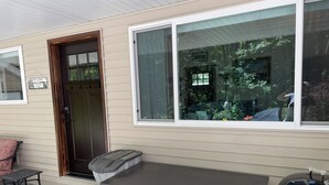 Une maison avec une porte d’entrée, une fenêtre, un barbecue et une petite table.