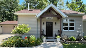 Une maison de plain-pied avec un porche à l’avant, un garage et une pelouse bien entretenue.