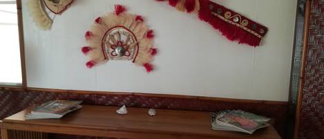Una stanza con uno scaffale in legno che espone riviste, un cesto di vimini e due decorazioni murali con frange e motivi circolari.