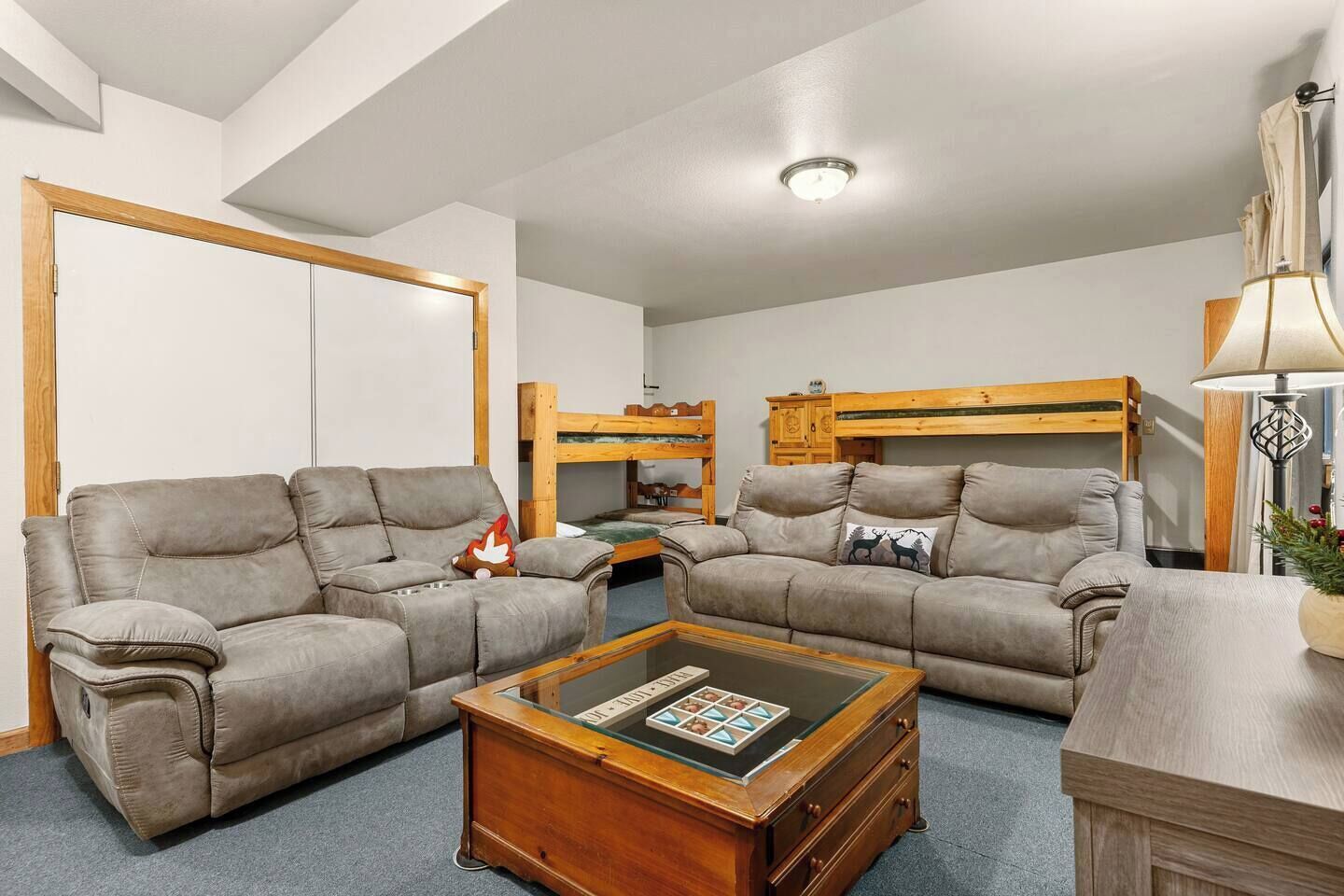 A spacious living room with two sofas, a coffee table, and a bunk bed in the background.