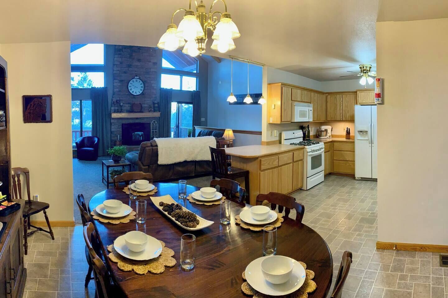 A spacious dining area with a wooden table set for a meal, a kitchen with modern appliances, and a cozy living room with a fireplace.
