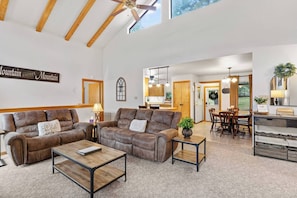 A spacious living room with a large brown leather sofa, a coffee table, and a dining area with wooden furniture. - Family Retreat - Balcony - Near White Sands - Wildlife - In Village (Cloudcroft)