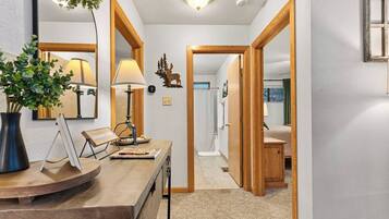 A hallway with a desk, lamp, and a plant. There are wooden doors leading to other rooms.