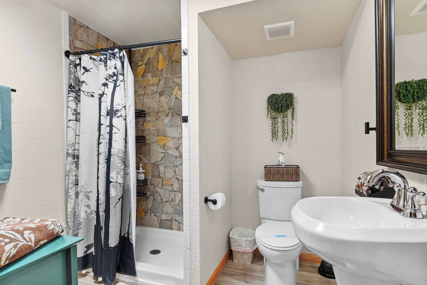A bathroom with a shower, toilet, sink, and a stone wall.