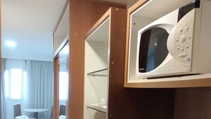 Cocina compacta con microondas, pileta y heladera pequeña.