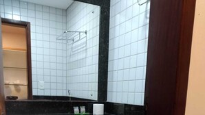 Un baño pequeño con azulejos, un inodoro blanco, una encimera negra y un espejo sobre el lavabo.