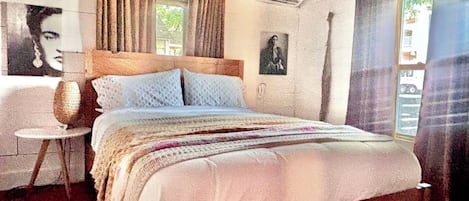 A bedroom with a wooden bed, a small round table, and a window with curtains.