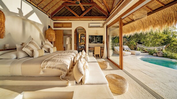 A spacious bedroom with a large bed, a TV, and a view of a pool. - Munay Wasi Uluwatu (Pecatu)