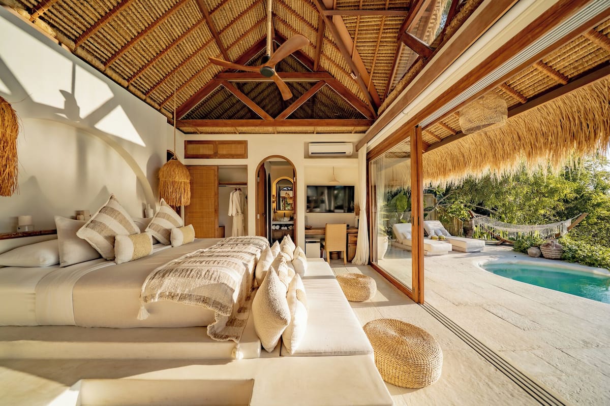 A spacious bedroom with a large bed, a TV, and a view of a pool.