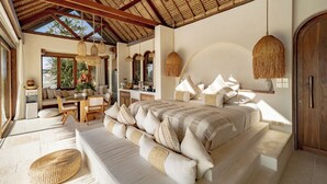 A spacious bedroom with a large bed, a sitting area, and a dining table. - Munay Wasi Uluwatu (Pecatu)