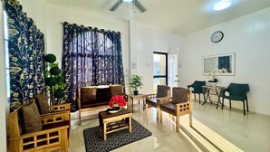 A living room with a sofa, chairs, a coffee table, a potted plant, and a ceiling fan.