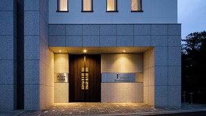 Un edificio moderno con una puerta de entrada de madera oscura, ventanas iluminadas y un cartel que dice 