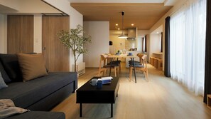 A modern living room with a sofa, coffee table, and dining area with chairs and a table. - Minn Kitahiroshima Station East (Kitahiroshima)