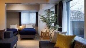 Una habitación de hotel moderna con una cama grande, un sofá, una mesita y una planta en maceta.