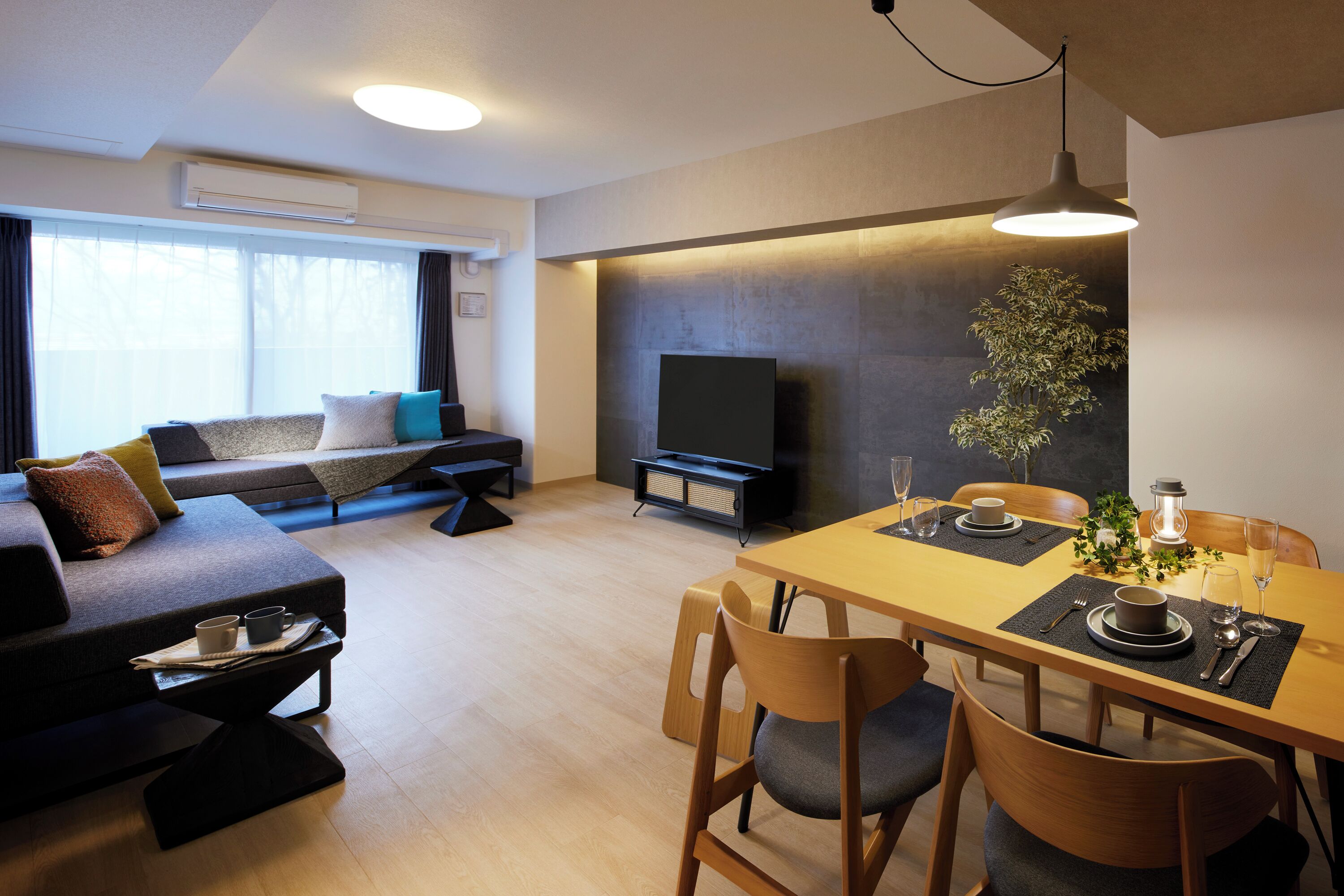 A modern living room with a sofa, dining table, and TV.