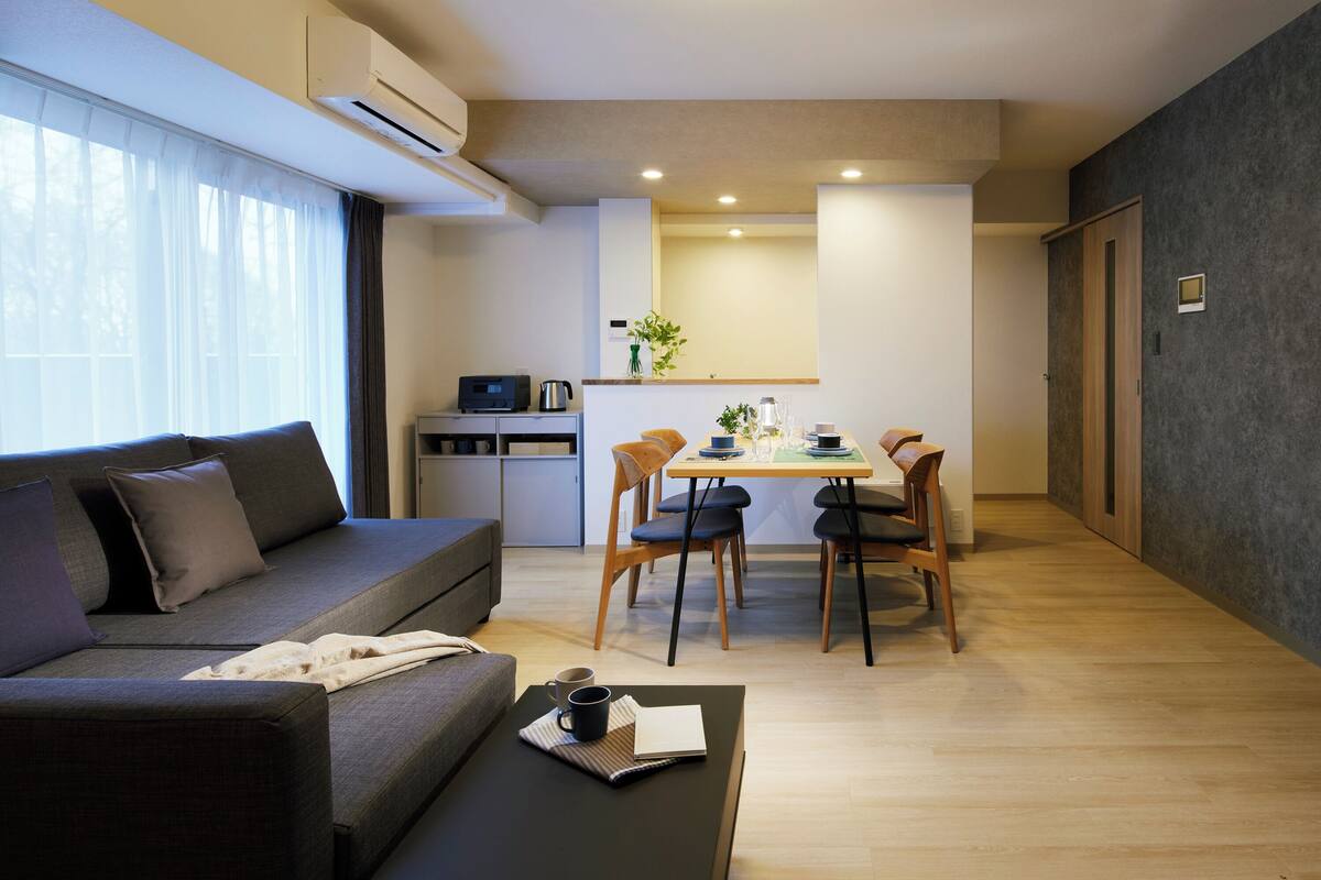 A modern living room with a sofa, coffee table, and dining area.