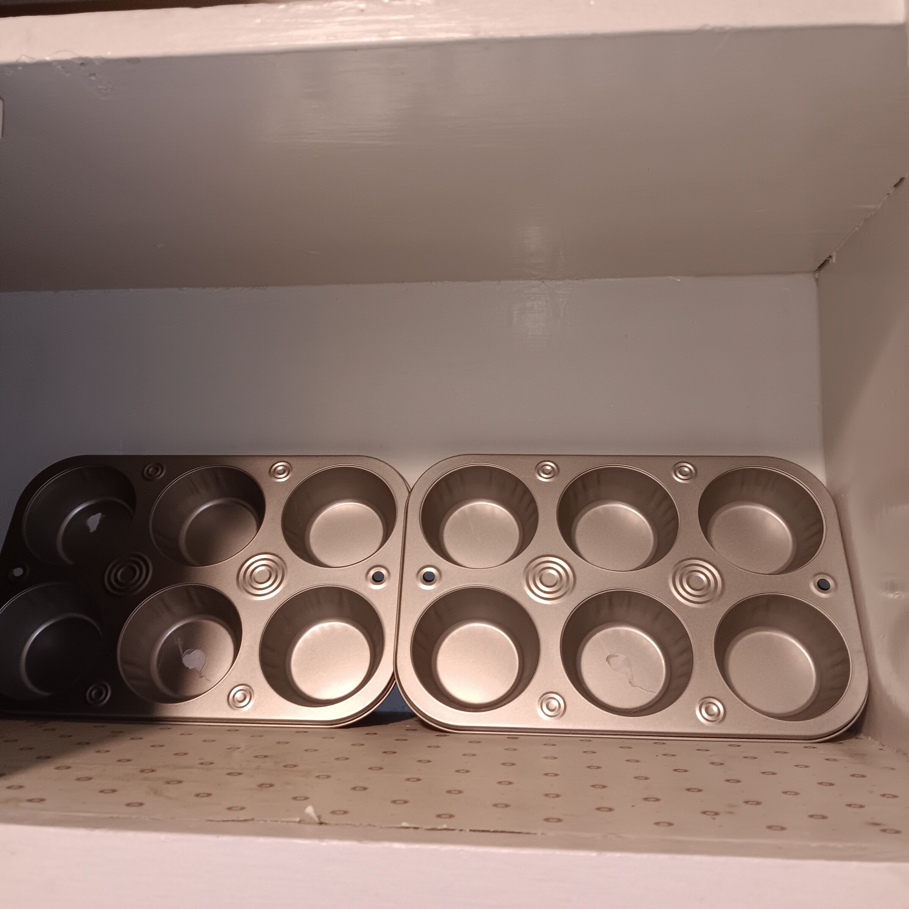 Una estant amb sis motlles metàl·lics per muffins.