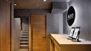 Una zona de recepción moderna con una puerta de madera, una escalera y un mostrador de recepción con dos monitores.