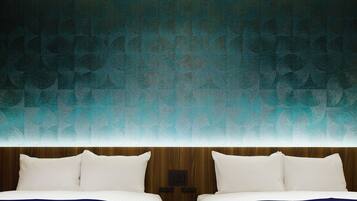 A hotel room with a patterned teal wall, two beds with white linens, and a wooden headboard.