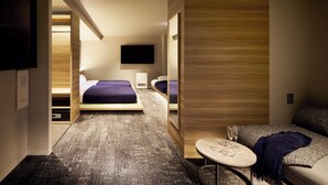 Una habitación de hotel moderna con una cama grande, un televisor, una mesita con vasos y un sofá.
