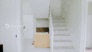 A staircase leading to a landing with a white wall and a wooden door.