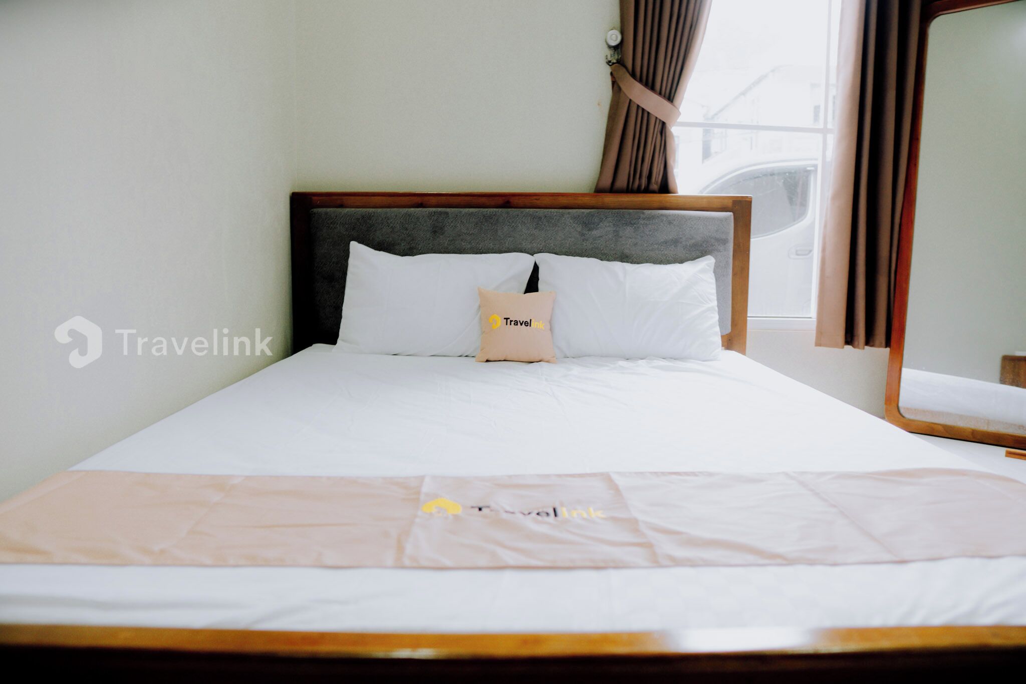 Una cama bien hecha con una almohada y una manta, ambas con la marca Travellink.