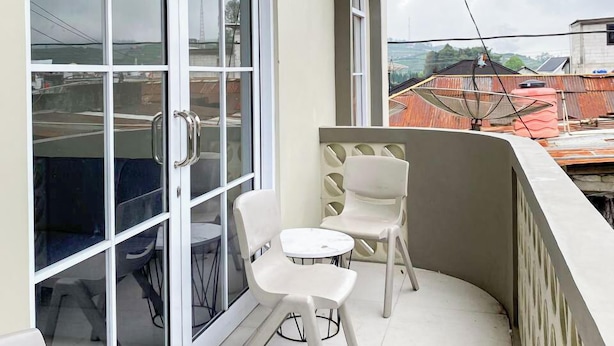 Een balkon met een glazen deur, twee witte stoelen en een kleine tafel.