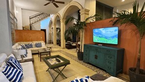 A living room with a sofa, coffee table, TV, and a staircase.
