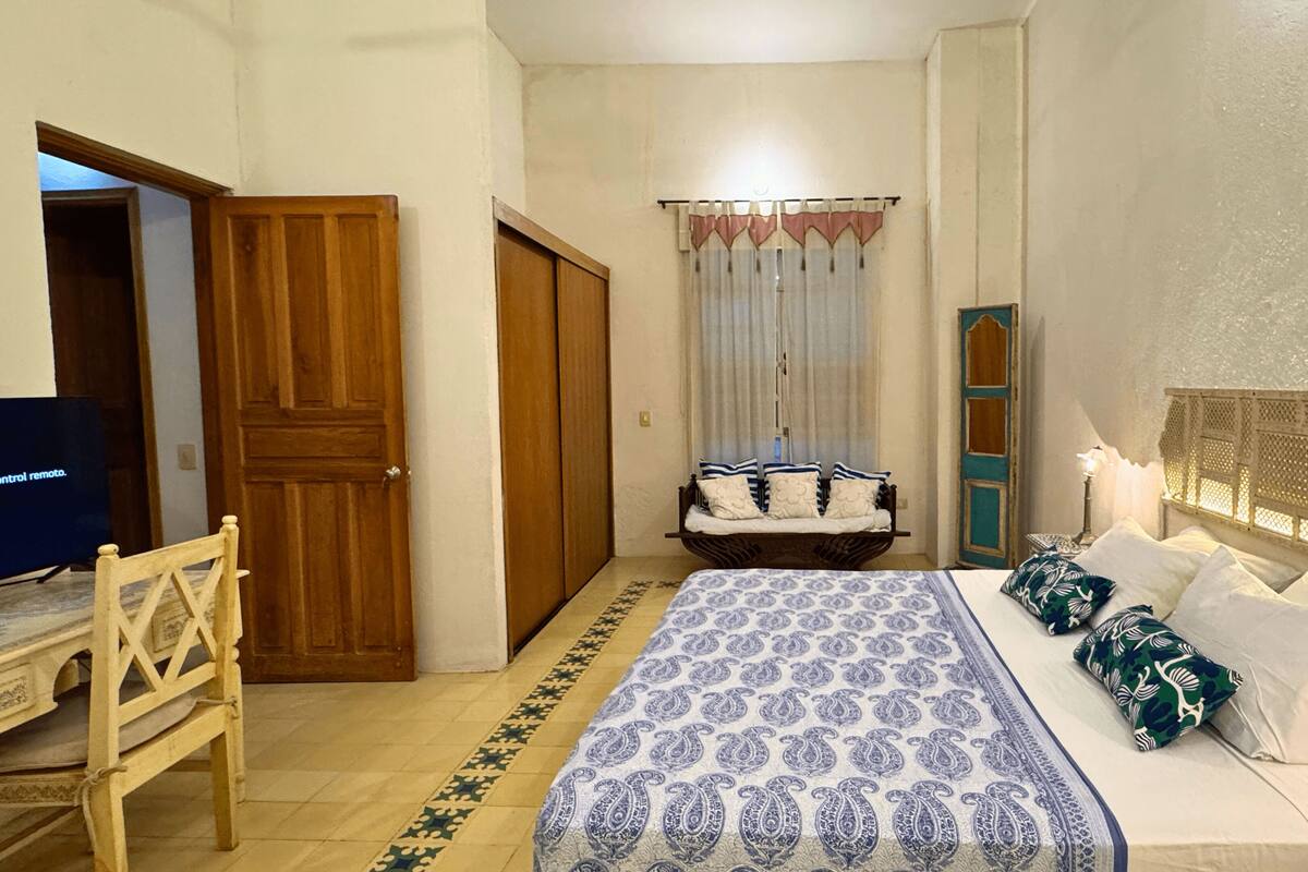Un dormitorio con cama, mesita de noche, lámpara y una silla.