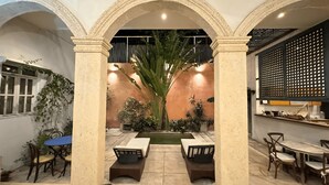 A courtyard with a pool, seating area, and a dining setup.