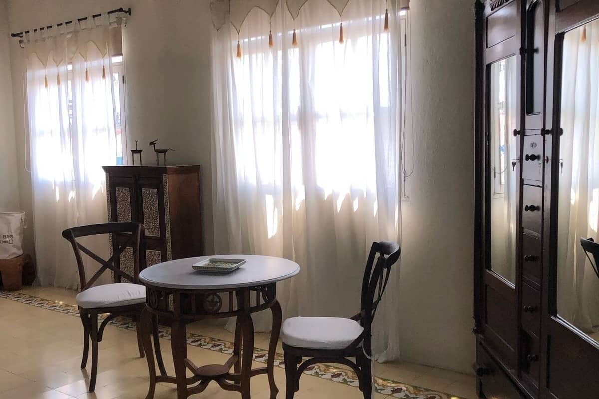 Un área de comedor con una mesa redonda y cuatro sillas, un armario y un ventilador de techo.